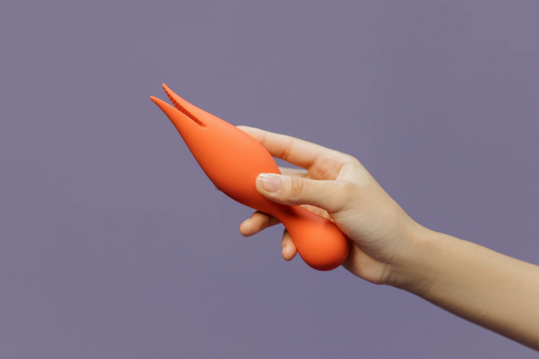 Mão segurando vibrador de limão contra fundo roxo minimalista, mostrando sensualidade moderna
